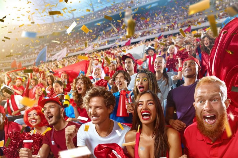 Young sport supporter happy fans cheering at stadium. Group of young woman and man support the football team during the match