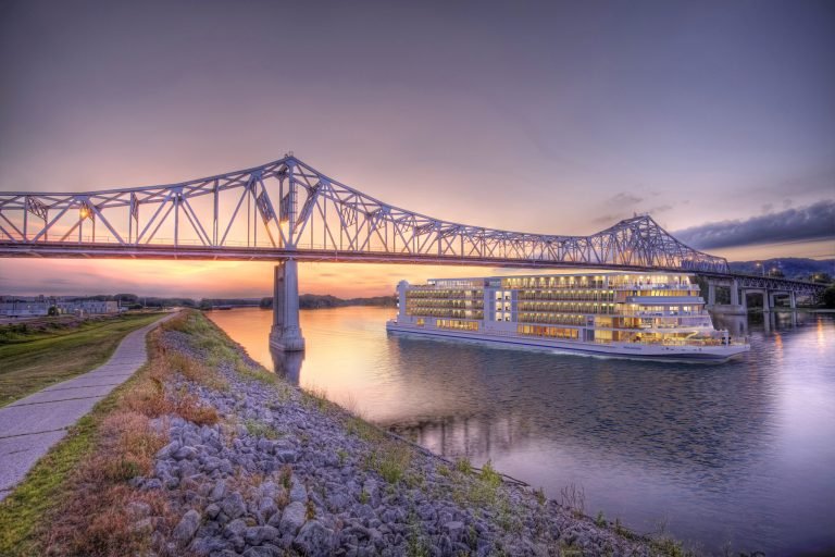 Viking river ship passing under a bridge at sunset
